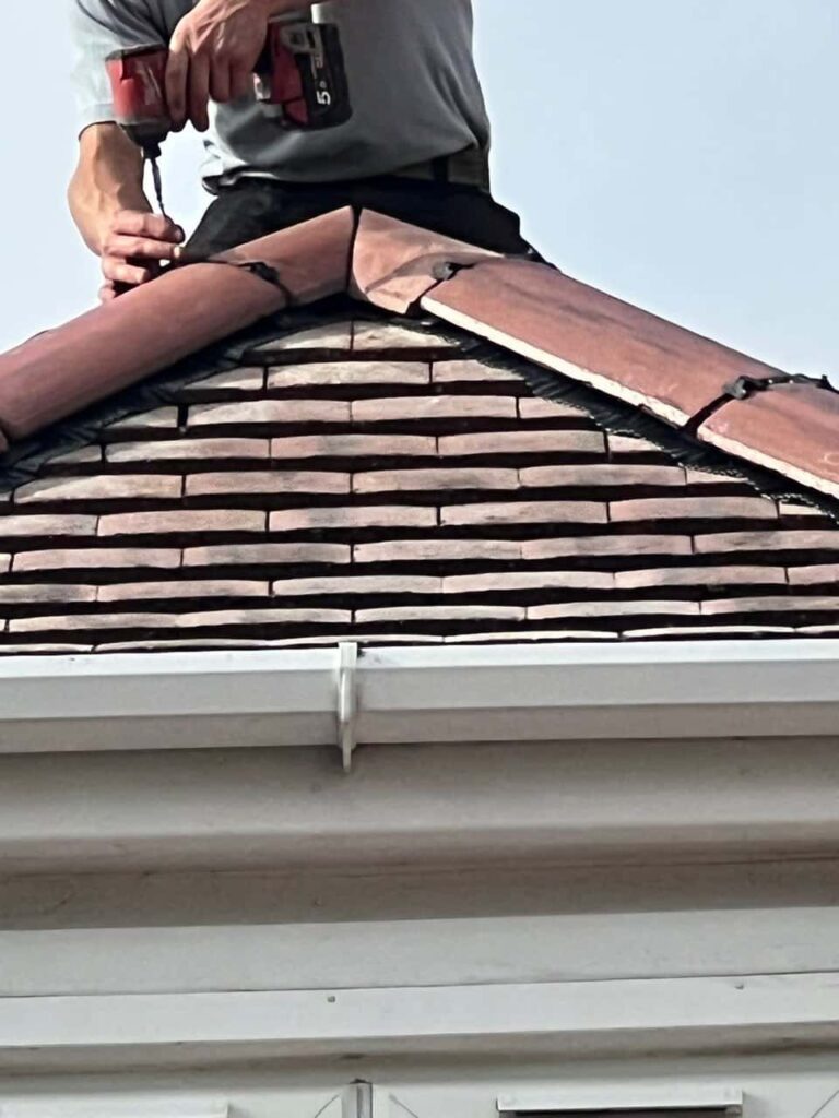 This is a photo of one of the operatives of LS Roofing Amersham installing new ridge tiles